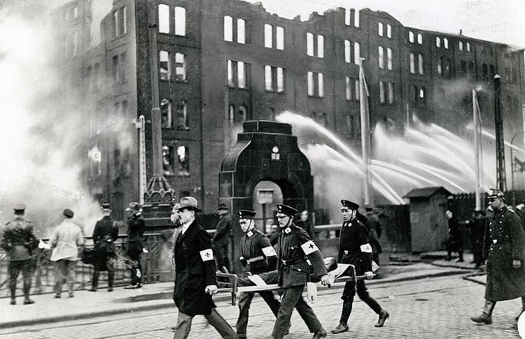 Feuer im Duisburger Hafen: DRK-Helfer transportieren einen Verletzten auf einer Trage, um 1930