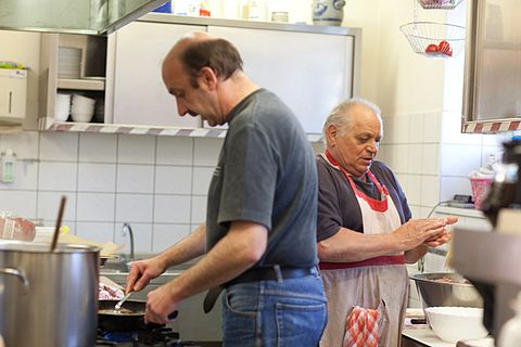 Obdachlose beim Kochen in der Küche einer Wärmestube des DRK im Oberallgäu