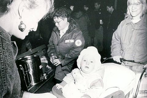 Ankunft von Flüchtlingen aus der DDR, vermutlich am Bahnhof von Ahrweiler bei Bonn. Im Hintergrund eine freiwillige Helferin des DRK bei der Ausgabe von heißen Getränken