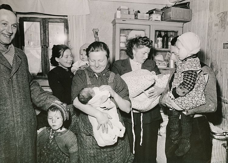 Nachkriegszeit in Deutschland: Mütter und Kleinkinder in Ansbach, nachdem sie Kleidung und Lebensmittel aus Schweden empfangen haben, um 1950