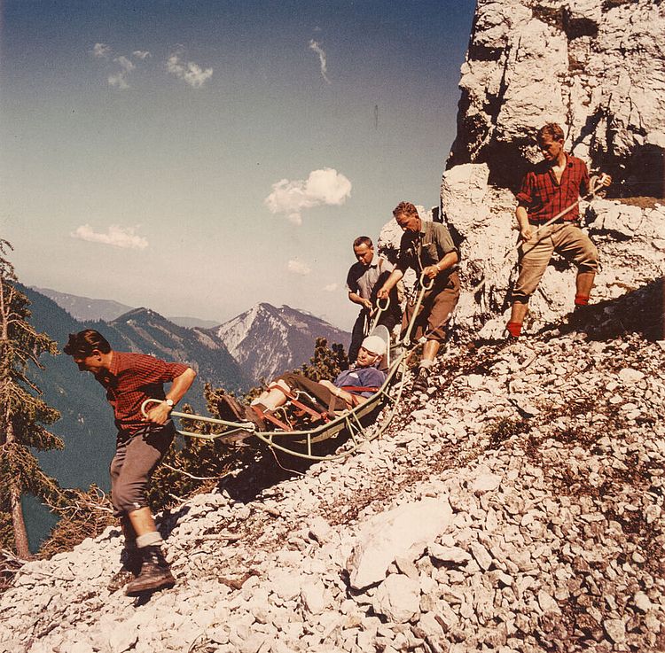 Einsatz der Bergwacht: Helfer beim Transport eines verunglückten Bergsteigers mit einer Gebirgstrage, um 1960