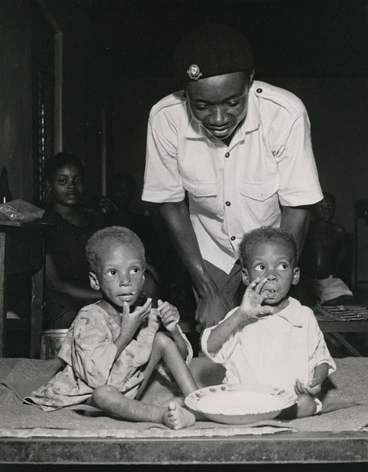 Zwei Kinder in einem Lager werden von einem Helfer des Nigerianischen Roten Kreuzes versorgt